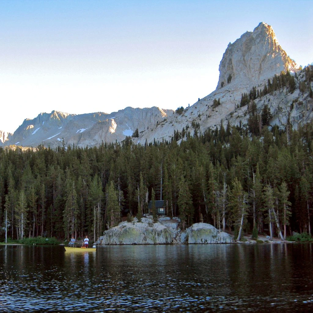 Alpine lake reflecting snow-capped peaks at dawn, from the First Light collection