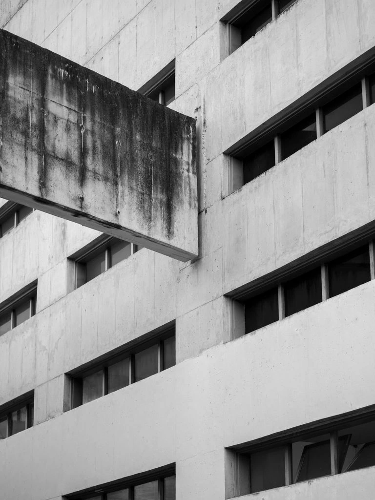 A raw concrete brutalist facade with a single porthole window, from the Minimalist Brutalism collection